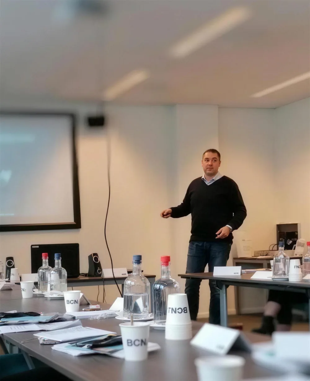 Arnoud Kuipers geeft een lezing aan een kleine groep rond een vergadertafel